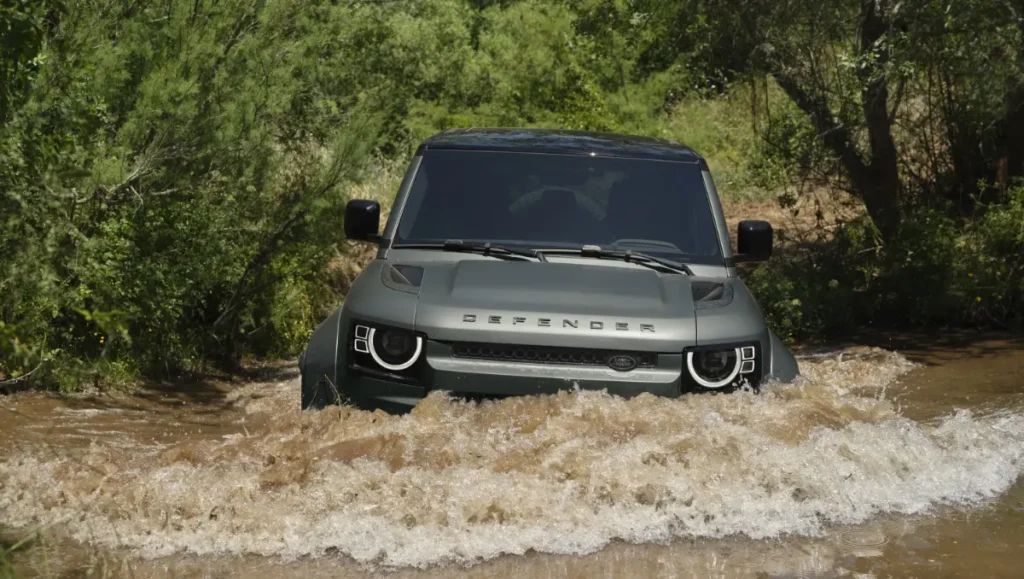 Land Rover Defender crossing water stream during premium off road driving adventure experience