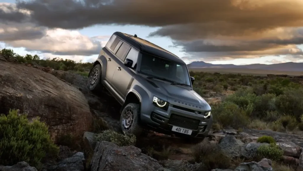 Land Rover Defender climbing rocky terrain during premium off road driving adventure in rugged landscape