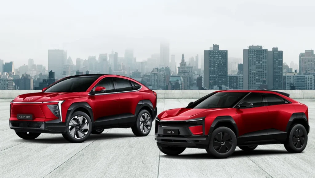 Mahindra XEV 9e BE6 anniversary offers showcased with red electric SUVs against a city skyline