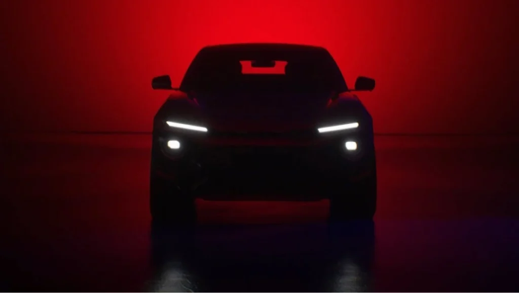 Mahindra Teases A New BE Model dark teaser image showing electric SUV front silhouette with LED lights