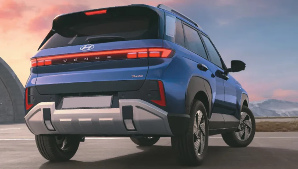 2025 Hyundai Venue rear right view in blue showing connected LED tail lamps and sporty design